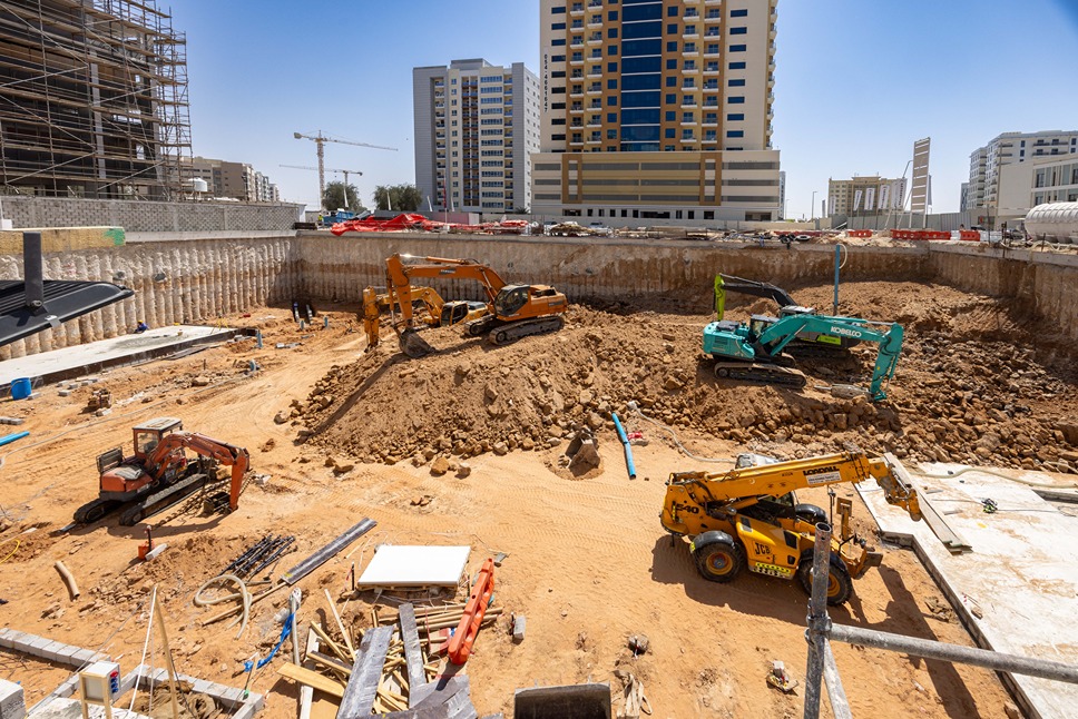 Cove Edition I By Imtiaz 1 A construction site featuring heavy machinery, including excavators and cranes, amid a large earth excavation area.